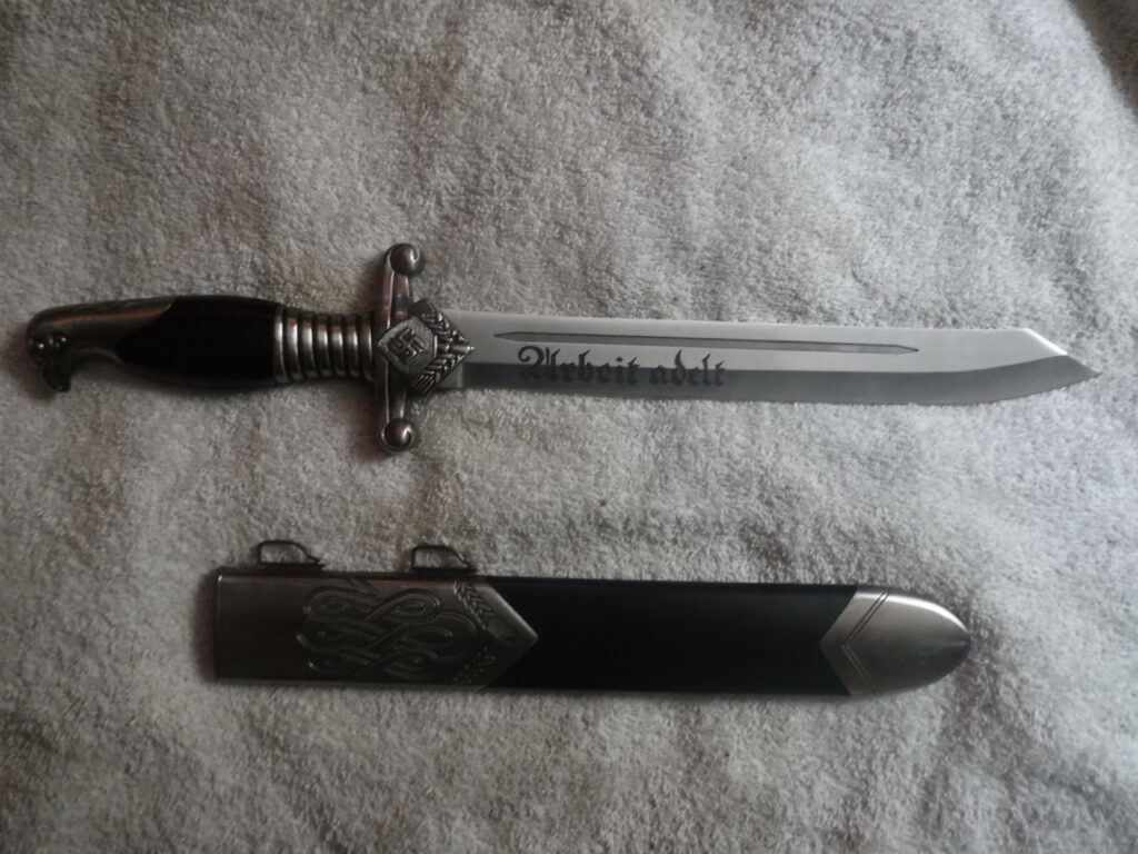 Nazi WW2 RAD dagger with sheath. Swastika and eagle head on handle. Blade etched Urbeit Adelt, roughly translates to 'work is good'