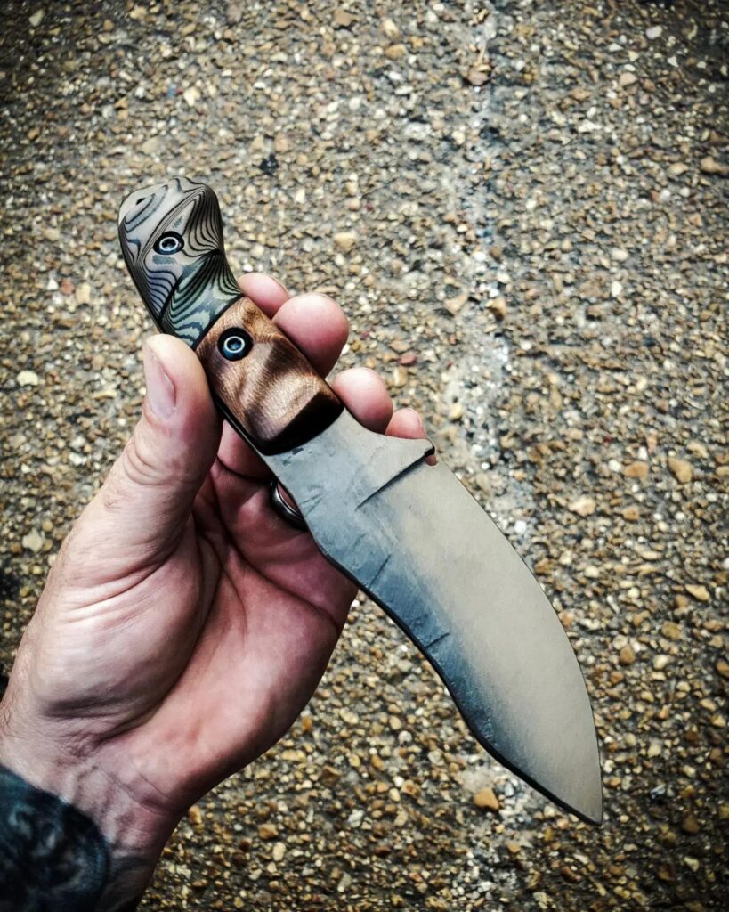 80crv2, Cerakote finish with distressed burnt bronze. The handles Curly Redwood and some OD green and black, and Earth brown and black layered G10, black G10 liners.