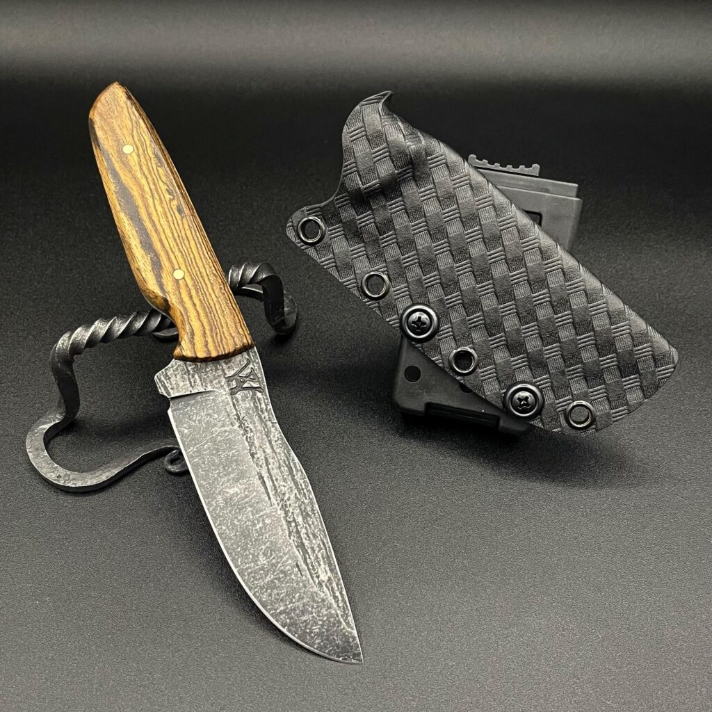 Bocote hardwood with brass pins on a 80crv2 drop point. Sheathed in basketweave Kydex
