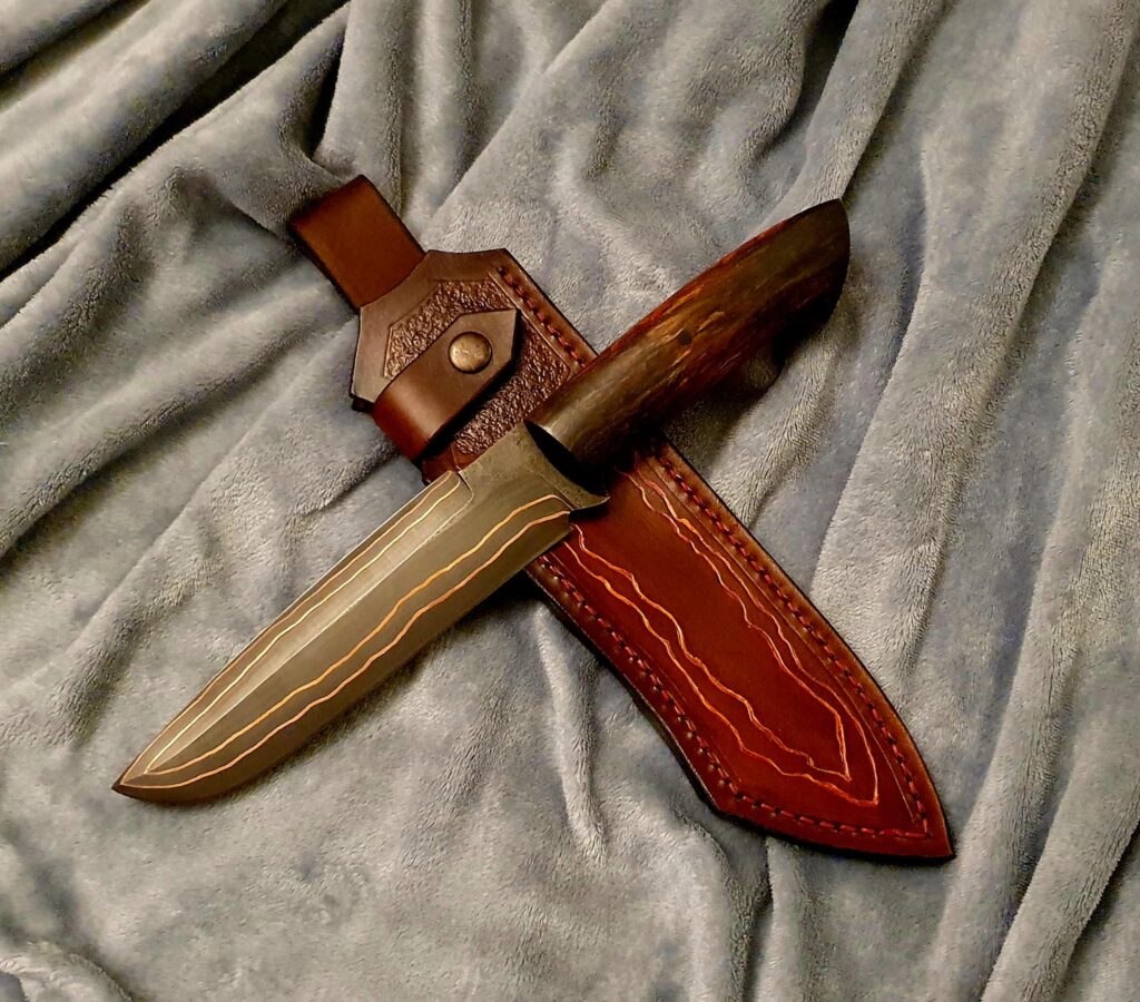 Copper damascus with 52100 core and stab birch. Finalized with sheath.