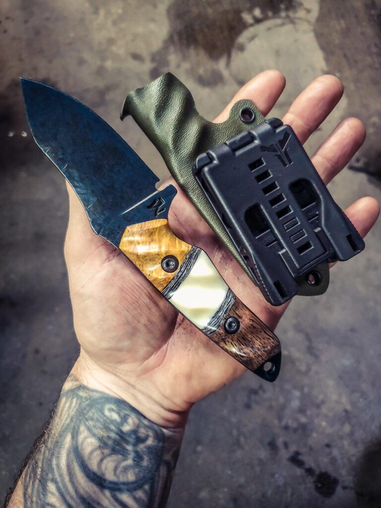80crv2 stone washed, then cold blued over, handles Natural Box elder and some Apocalyptic Mango, the split is white infused carbon fiber and stablized walrus tusk. Black G10 liners👍