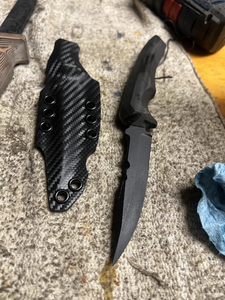 Blacked out 8670 steel blade, carbon fiber style sheath. Just finished. Micarta handles pinned in place. Thanks for looking.