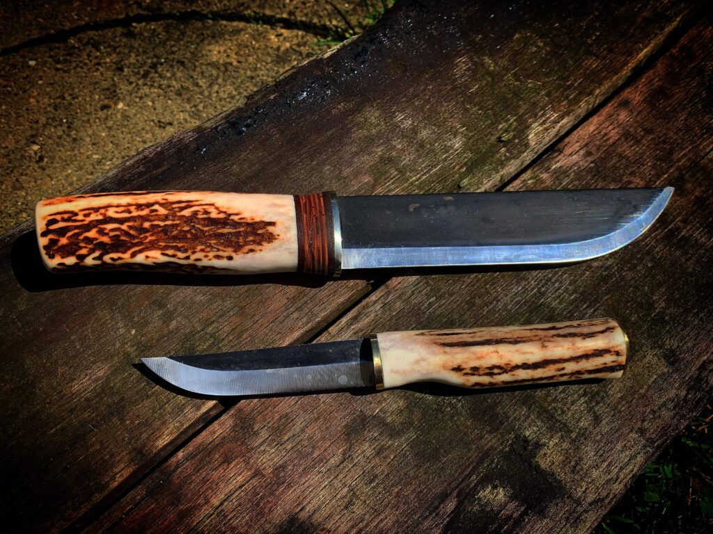 Two homemade knives. Both made with Lauri blades, deer antler and birch bark.