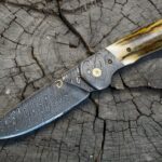 F style Hunter with ADS damascus blade and matching bolsters. Mammoth ivory for scales. Ti screws and a cool pivot pin. The sheath is tooled leather with a very soft pig skin lining. OAL is 9 inches and the blade is 4 1/8