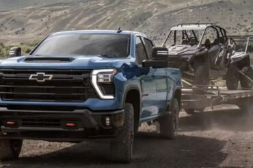 2027 Silverado HD and Sierra HD: Silverado HD towing an off-road trailer on a rugged mountain road