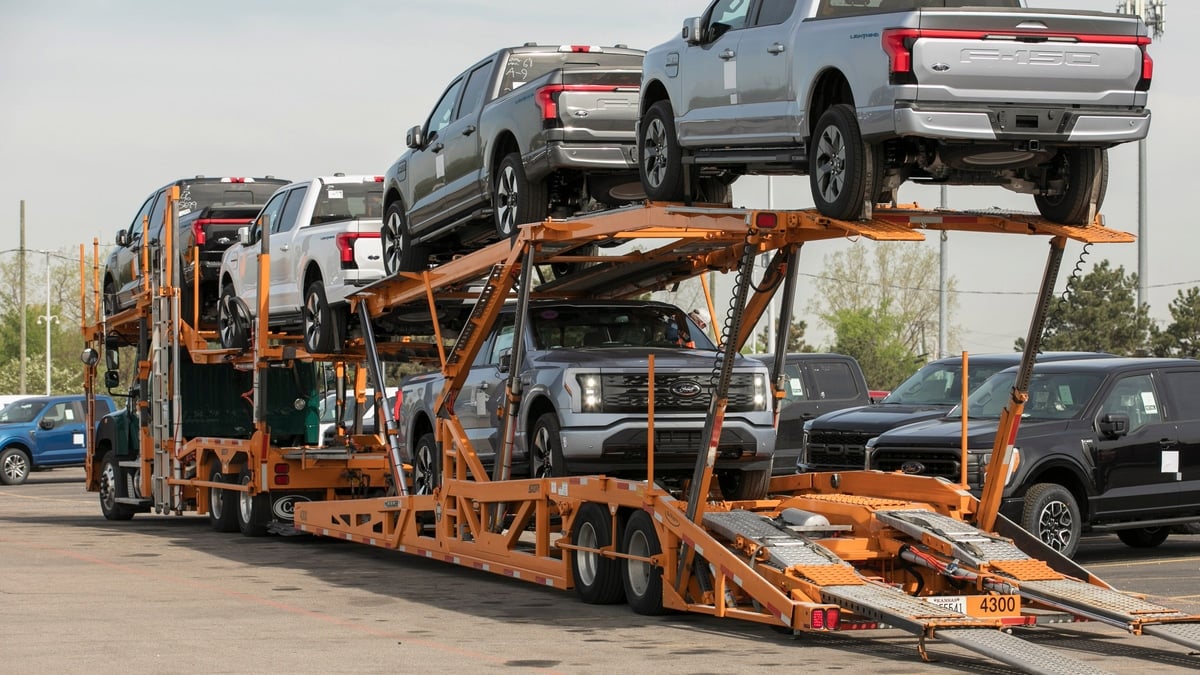 Ford F-150 Lightning electric pickups loaded onto vehicle transport trucks.